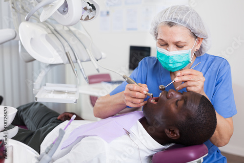 Dentist professional filling teeth for man patient sitting in medical chair. High quality photo