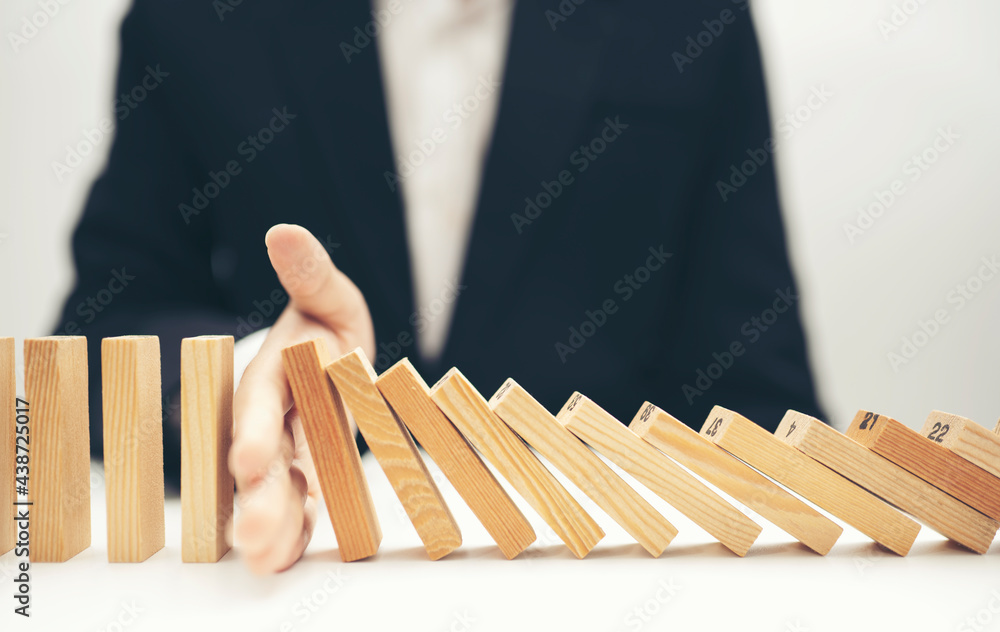 Close up businessman hand stop dominoes continuous toppled