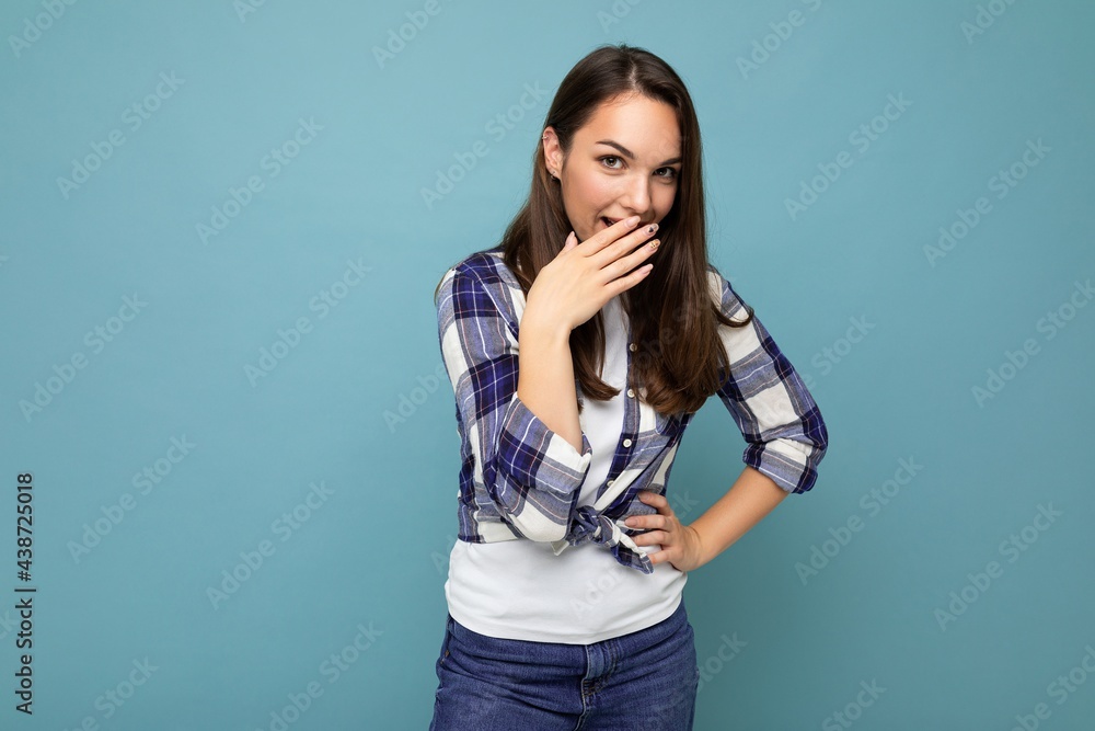 Photo of young positive happy attractive pretty brunet woman with sincere emotions wearing stylish check shirt standing isolated on blue background with empty space and laughing Photo of young positive happy attractive pretty brunet woman with sincere emotions wearing stylish check shirt standing isolated on blue background with empty space and laughing