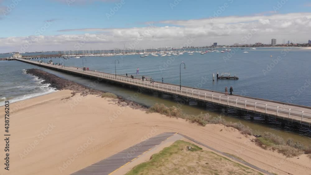 Aerial orbiting shot showing coast of St Kilda Beach in with sandy beach,ocean water and Melbourne Skyline in background during sun Aerial orbiting shot showing coast of St Kilda Beach in with sandy beach,ocean water and Melbourne Skyline in background during sun
