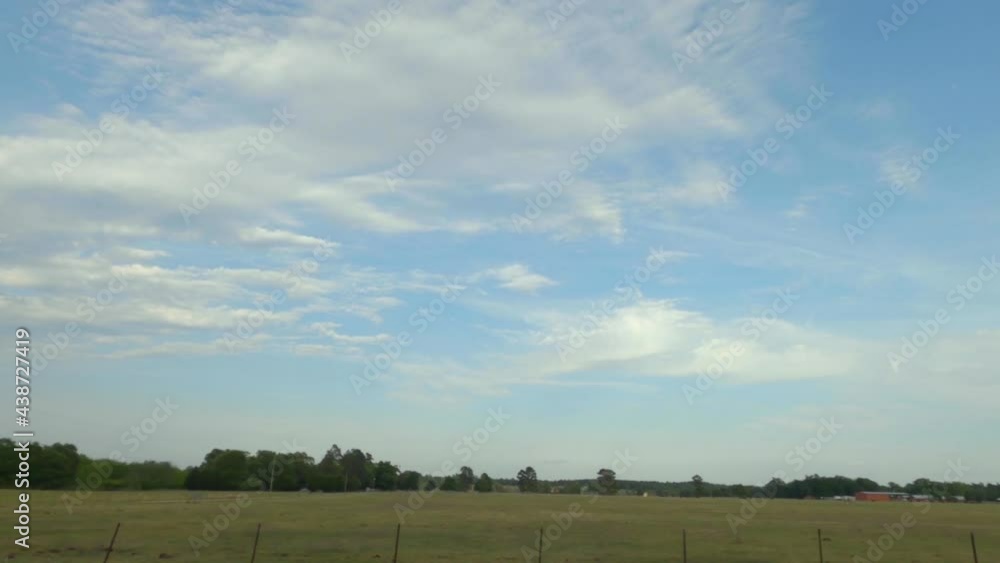Pan of beautiful farmland and distant buildings with cloudscapes and green pastures behind a wooden wire brown fence Pan of beautiful farmland and distant buildings with cloudscapes and green pastures behind a wooden wire brown fence