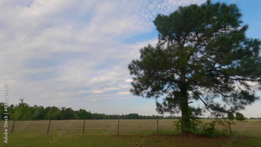 Pan of beautiful farmland and cloudscapes and a brown wire fence in rural Georgia Pan of beautiful farmland and cloudscapes and a brown wire fence in rural Georgia