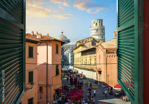 View through an open window with shutters of the Leaning Tower of Pisa and Duomo dome from a room along Via Santa Maria, in Pisa Italy