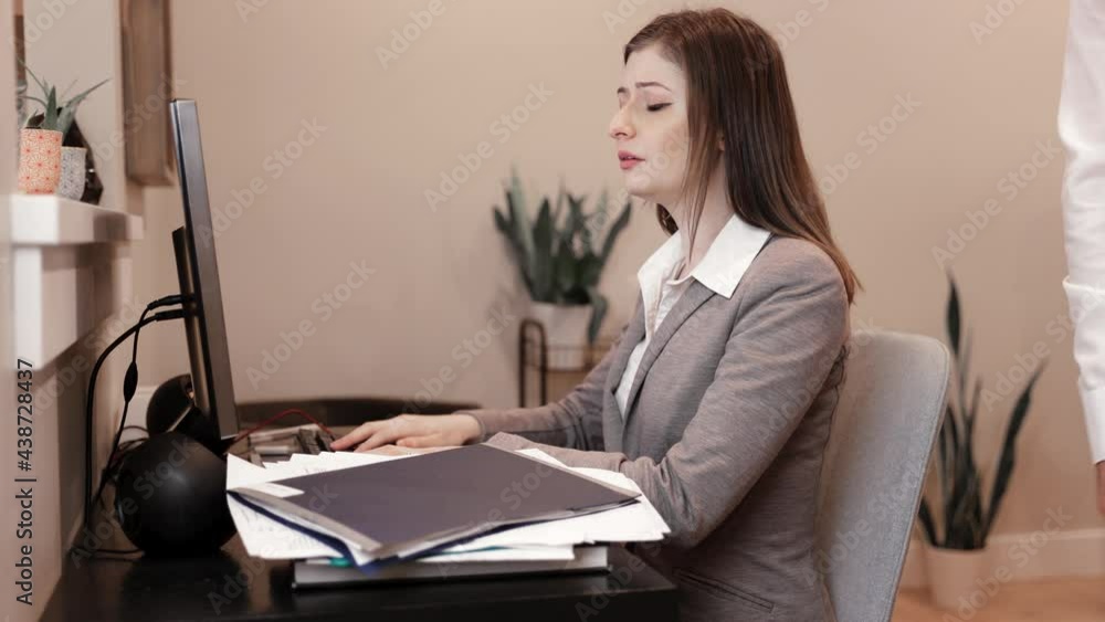 Young professional woman at office desk, computer, typing, stack of paperwork, overworked, tired, stressed out, corporate life. 4K 24FPS.