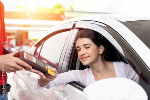 Woman customer paying by credit card gas station. Refuelling car and service payment with wireless bank payment terminal concept photo