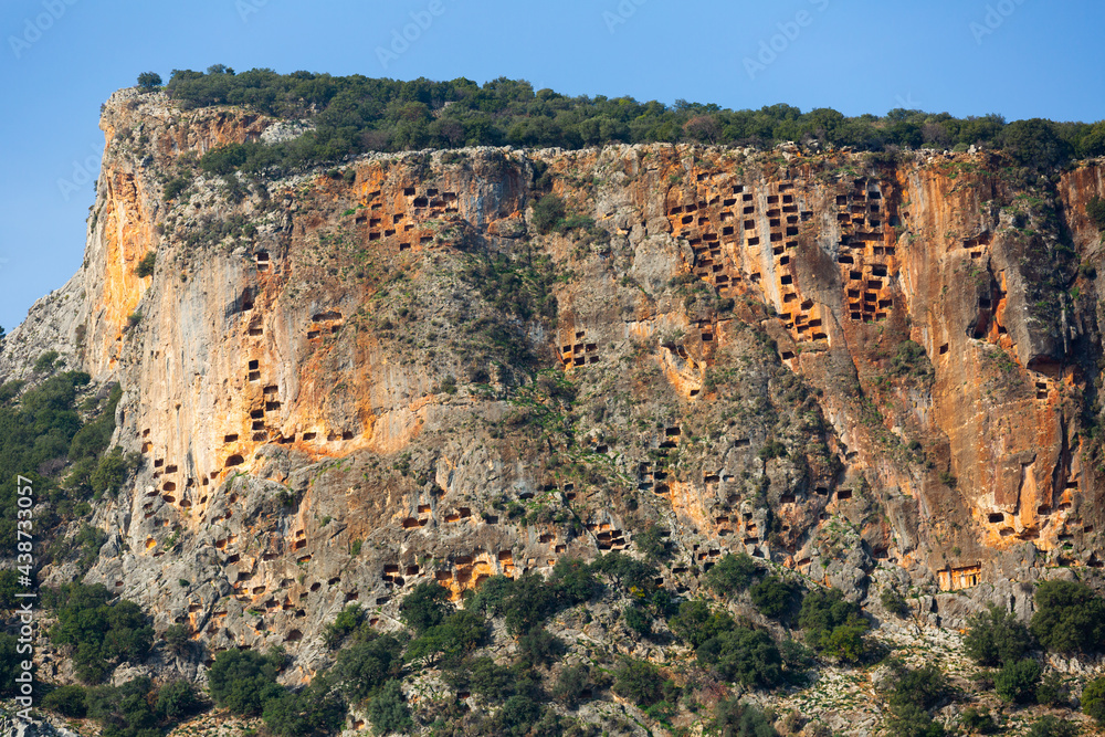 View of hundreds of burial tombs carved into mountainside in ancient Lycian city of Pinara in Turkey