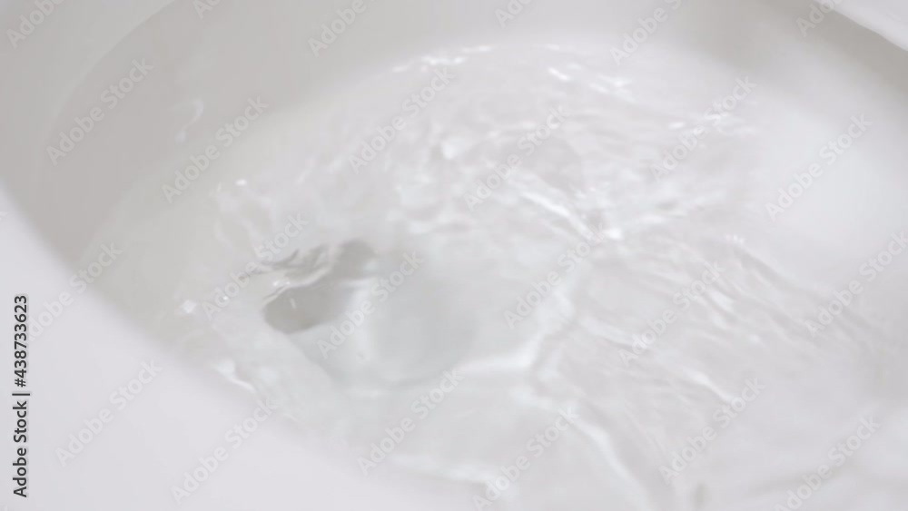 A white toilet brush is being moved in circles inside the white toilet to clean it and disinfect it. The transparent water moves during. Housekeeping in a hotel room. A white toilet brush is being moved in circles inside the white toilet to clean it and disinfect it. The transparent water moves during. Housekeeping in a hotel room.