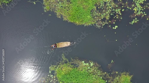 Aerial view of a small fishing boat sailing in a swamp river inlet on waterlilies farm and culture in Sirajdikhan township, Dhaka, Bangladesh.