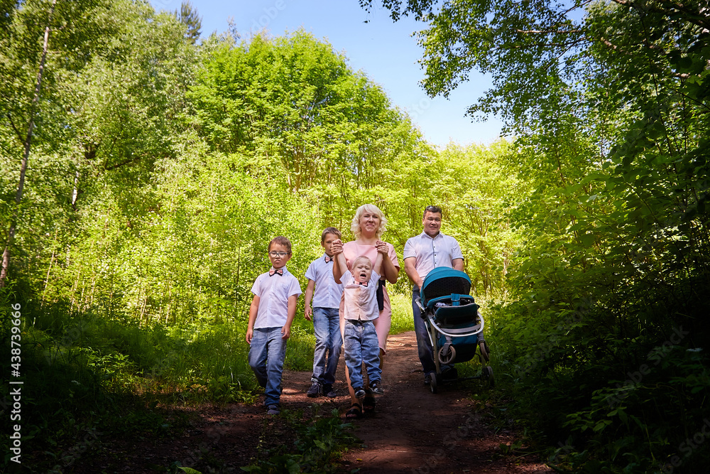 Fun walk of large family in the summer forest. Mother, father, brothers walking in the park or forest on a sunny day Fun walk of large family in the summer forest. Mother, father, brothers walking in the park or forest on a sunny day