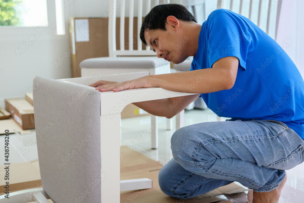 Man assembling white chair furniture at home