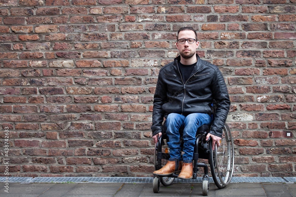 man in wheelchair in front of brick wall