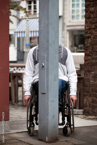 Man in wheelchair hiding behind metal post