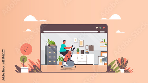 man riding stationary bike guy having cardio workout online training healthy lifestyle home sport concept