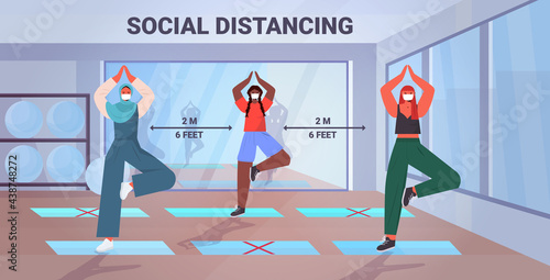 mix race girls in masks doing yoga exercises keeping distance to prevent coronavirus social distancing