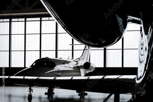 Luxury private jet plane storage inside the hangar. Natural black and white high contrast. 
