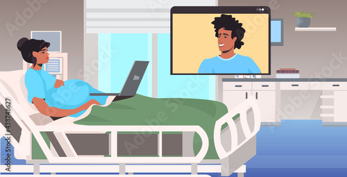 pregnant woman in hospital bed chatting with man in web browser window during video call online meeting