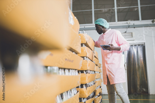 African american worker inspecting production line at drinks production factory. working Concept. workers checking juice bottles before shipment. Inspection quality control.