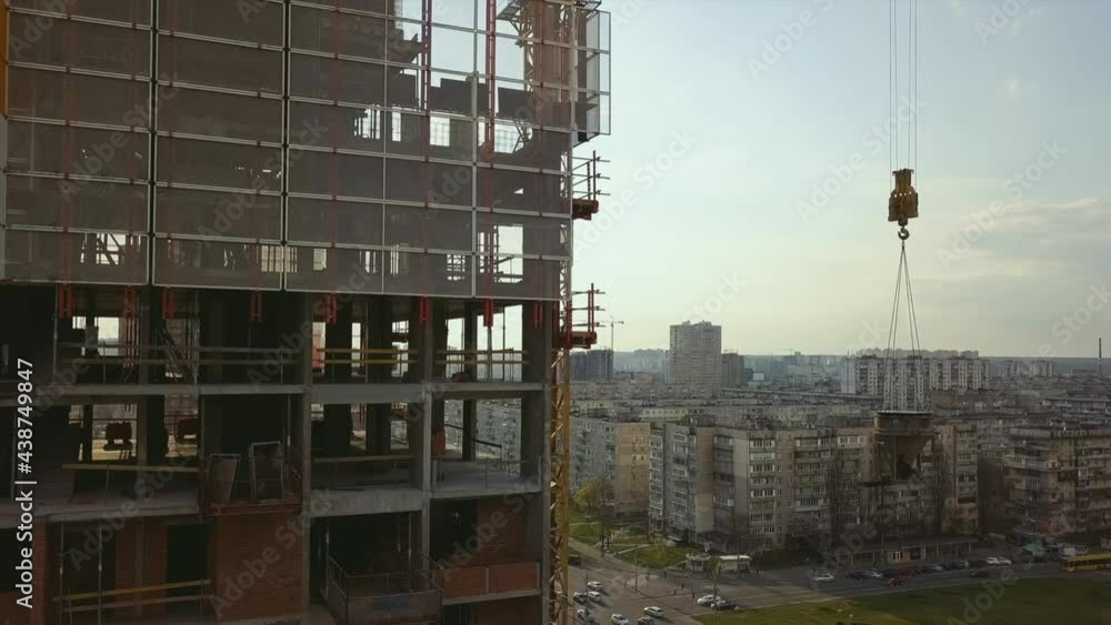 Raising a cistern with concrete on the roof of a high-rise building under construction with workers in helmets against the backdrop of city life, in the backlight Raising a cistern with concrete on the roof of a high-rise building under construction with workers in helmets against the backdrop of city life, in the backlight