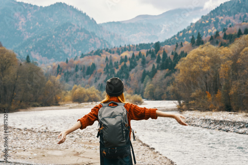 woman holding her hands above her head in the mountains outdoors in autumn near the river travel