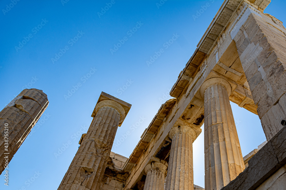 Low angle view of ancient temple columns against the sun and the blue sky