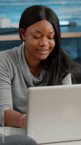 African student woman remote working from home while drinking coffee browsing webinar education composing culture email resolving social meadia problem. Black woman sitting on bean bag in living room photo