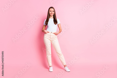 Full size photo of young beautiful smiling positive businesswoman hold hands pockets isolated on pink color background