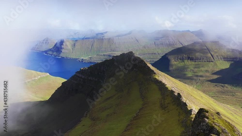 Drone flying through clouds. Aerial view of green grass mountain chain, in background blue sea and majestic landscape. backgrounds. Pristine nature