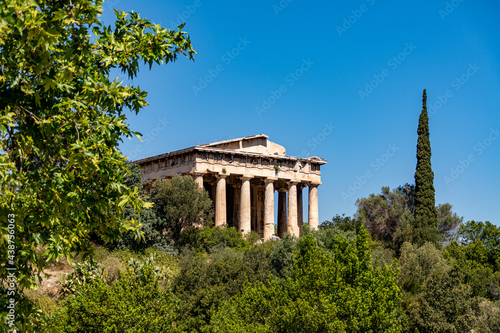 The Temple of Hephaestus, surrounded by green trees in spring, located on a hill in the ancient Agora of Athens, Greece
