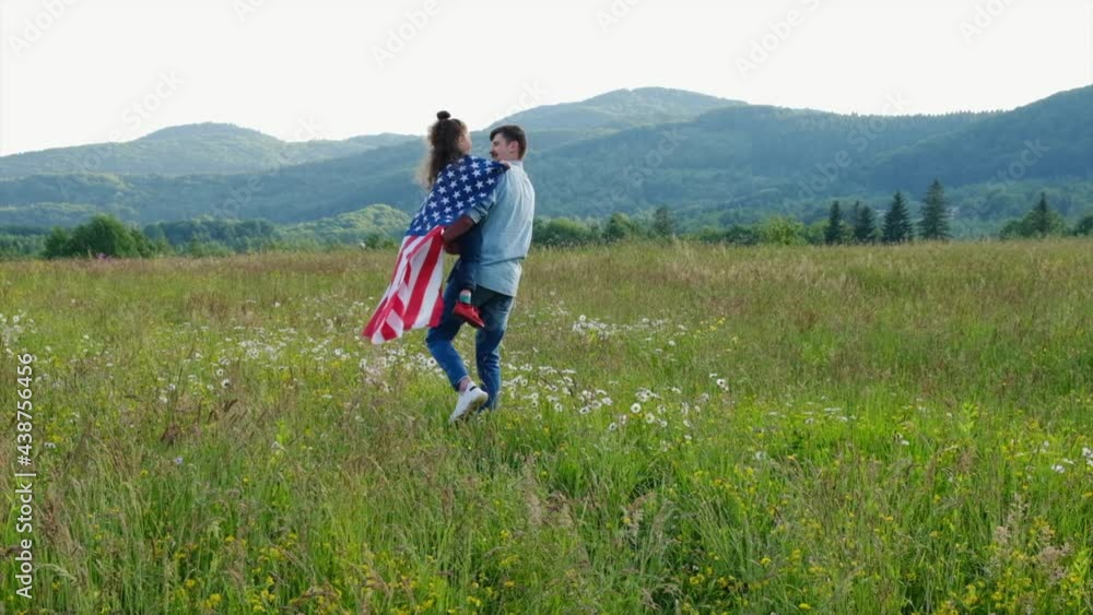 Attractive young father walking in flowers fields holds on hands adorable daughter with USA flag celebrates independence day on July 4 at nature. Cute little girl child spend time with loving dad Attractive young father walking in flowers fields holds on hands adorable daughter with USA flag celebrates independence day on July 4 at nature. Cute little girl child spend time with loving dad