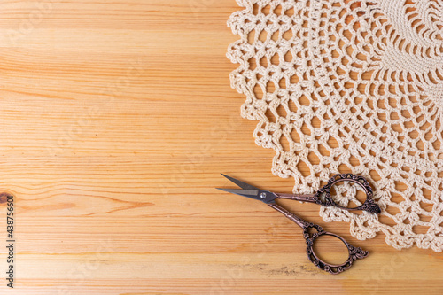 A knitted napkin and scissors on a wooden background. Needlework