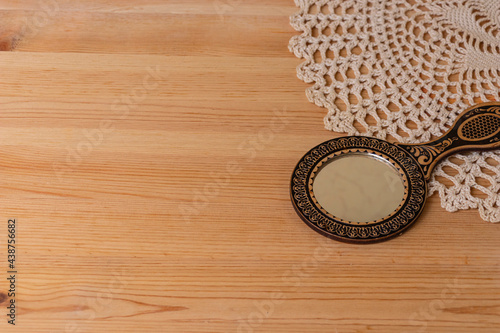 Women's dressing table in retro, vintage style. A mirror, a knitted napkin on the background of a natural wooden table.