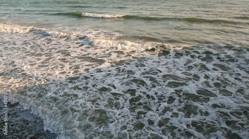 4k video top view of a wave near a pebble beach