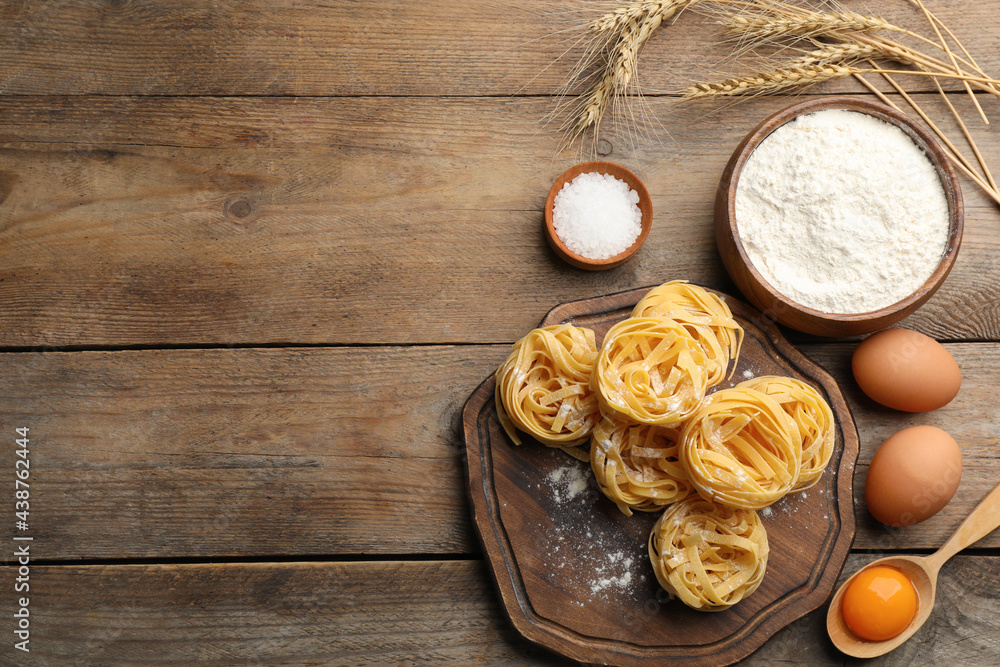 Flat lay composition with uncooked homemade pasta and ingredients on wooden table. Space for text Flat lay composition with uncooked homemade pasta and ingredients on wooden table. Space for text
