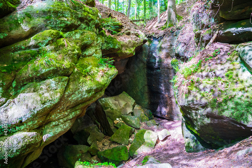 Germany, Gallengrotte cave in green forest landscape of kaisersbach ner welzheim with sunlight shining through the trees on the moss covered rocks photo