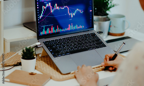 woman taking notes analyzing stock trading