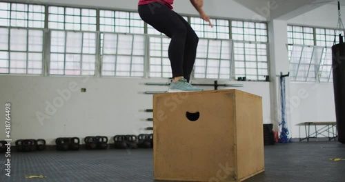 Fit caucasian woman jumping on pylo box at the gym photo