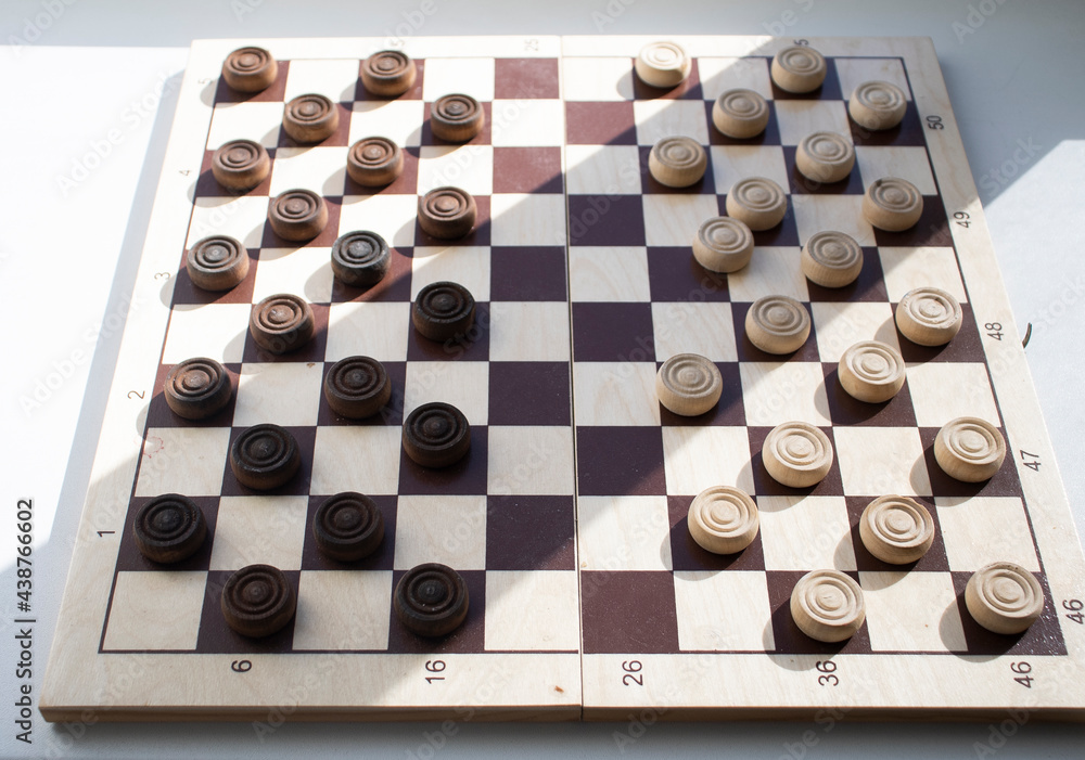 a wooden chessboard with white and brown checkers, on a light surface. Mind games, mental development and strategy. Games for children and adults. Chess school a wooden chessboard with white and brown checkers, on a light surface. Mind games, mental development and strategy. Games for children and adults. Chess school