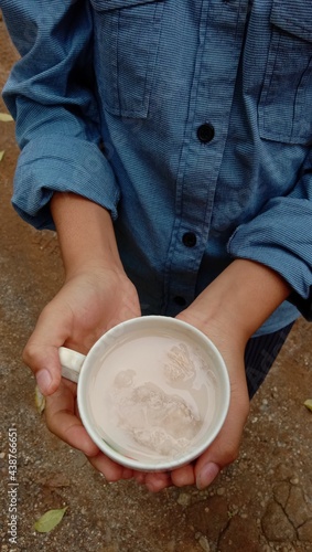 Photo of a person holding a cup filled with red soy milk