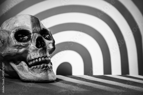Skull on a gray background with a podium and abstract blurred light stripes in the shape of an arch. Selective focus. Space for lettering, design, and presentation.