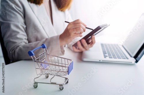 Online shopping. Gold credit card and smartphone in small shopping cart with icon customer network connection. Conceptual of internet shopping and e-commerce on wooden table background