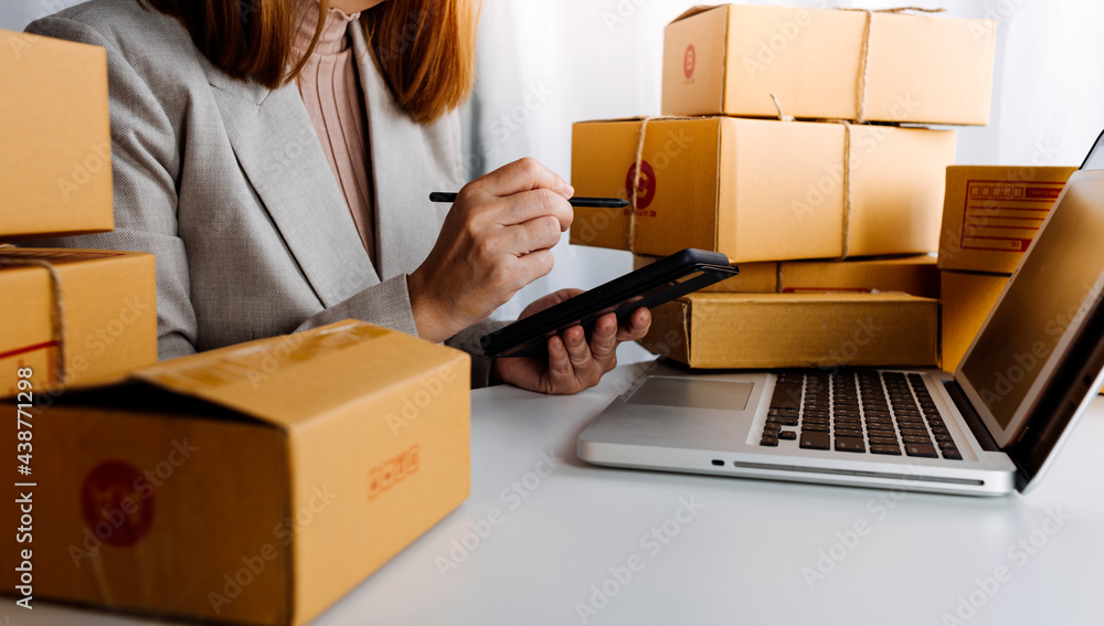 Young woman small business owner online shopping at home. taking note of orders from customers with mobile phones. SME entrepreneur or freelance life style concept. Young woman small business owner online shopping at home. taking note of orders from customers with mobile phones. SME entrepreneur or freelance life style concept.