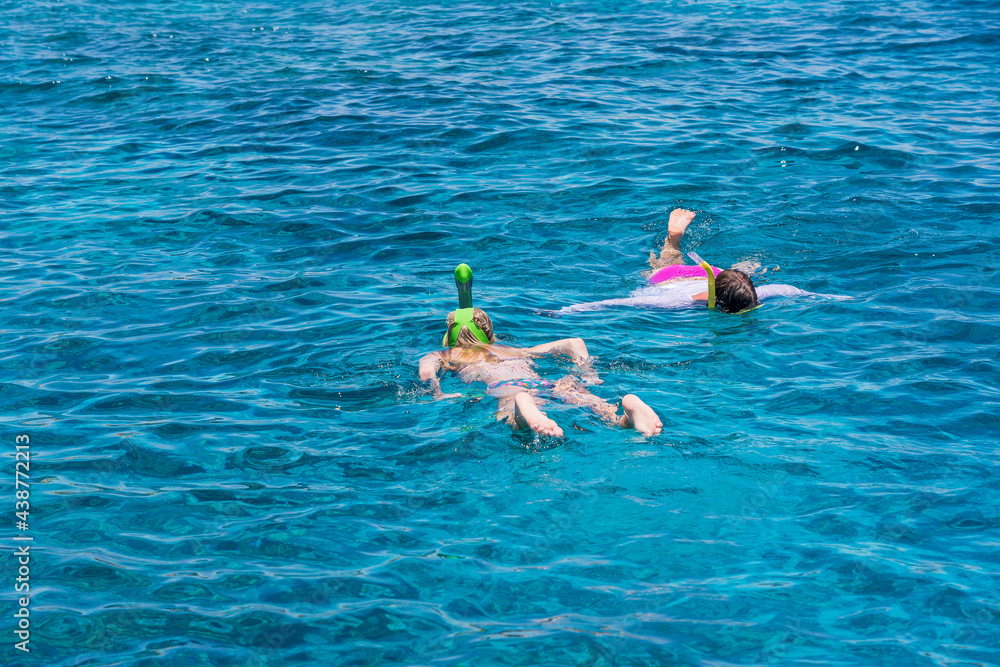Young girls snorkeling in blue clear waters above coral reef on red sea in Egypt. Travel and lifestyle concept
