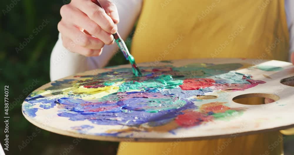 Midsection of caucasian woman painting in sunny garden Midsection of caucasian woman painting in sunny garden