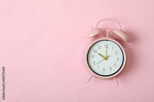 Alarm clock on pink background, space for text