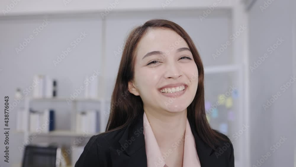 Slow-motion portrait of a beautiful Asian businesswoman is smiling and looking camera in the office. Successful and happy businesswomen. Slow-motion portrait of a beautiful Asian businesswoman is smiling and looking camera in the office. Successful and happy businesswomen.