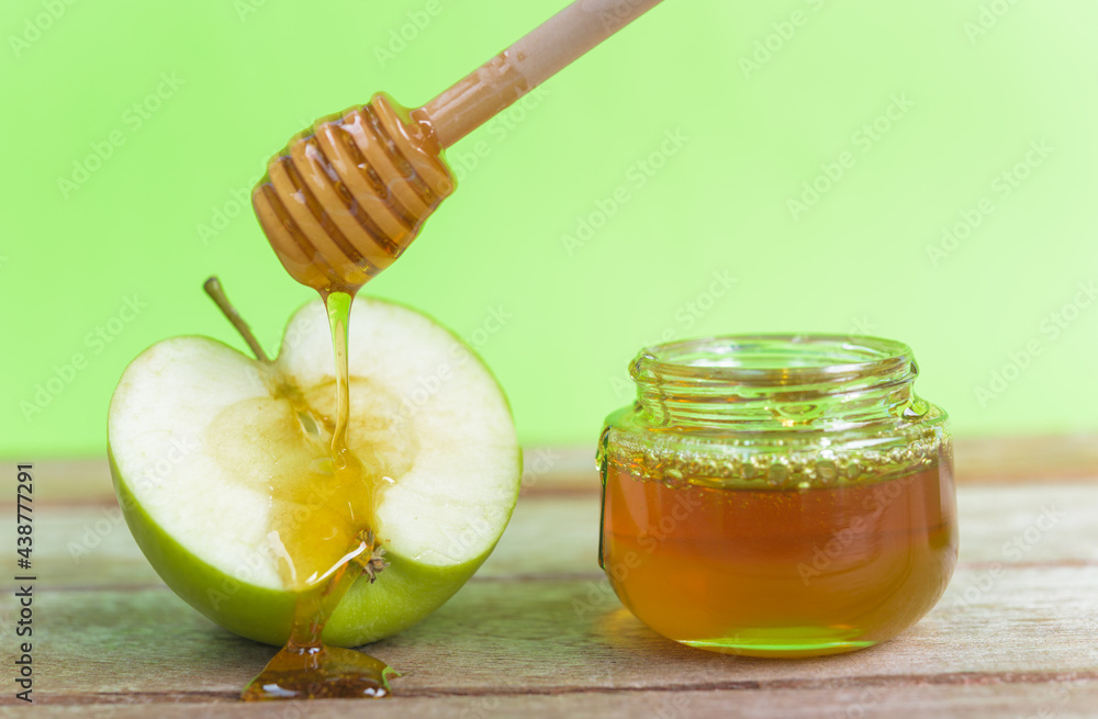 Jewish holiday, Apple Rosh Hashanah, on the photo have honey in jar and drop honey on green apples on wooden with green background Jewish holiday, Apple Rosh Hashanah, on the photo have honey in jar and drop honey on green apples on wooden with green background