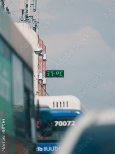 Traffic jam stuck in traffic with public bus and nig vehicle in hot weather 37 degree celcious building exterior thermometer green number photo