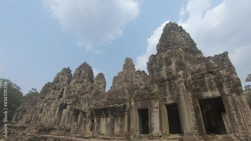 Carved stone temple, Angkor Wat , against blue sky. Tilt down shot