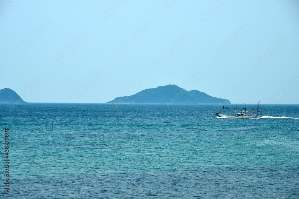 Obraz premium 日本海を帰港する漁船と島の風景