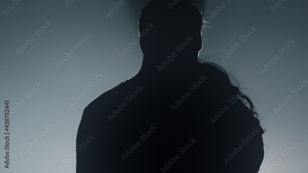 Silhouette couple dancing in dark space. Sensual lovers hugging indoors. Silhouette couple dancing in dark space. Sensual lovers hugging indoors.